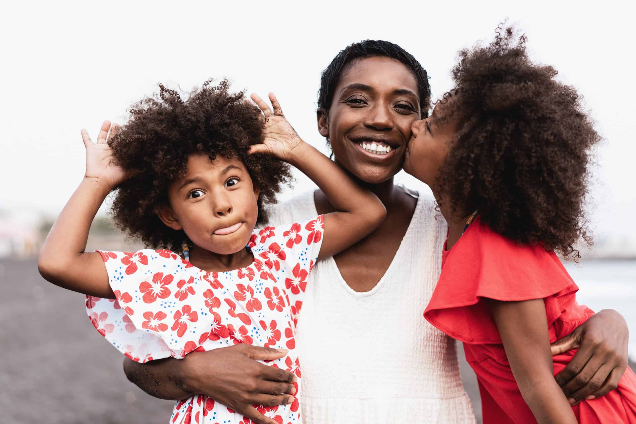 happy african sister twins kissing mother beach focus mother face scaled Smile Dentist Toronto