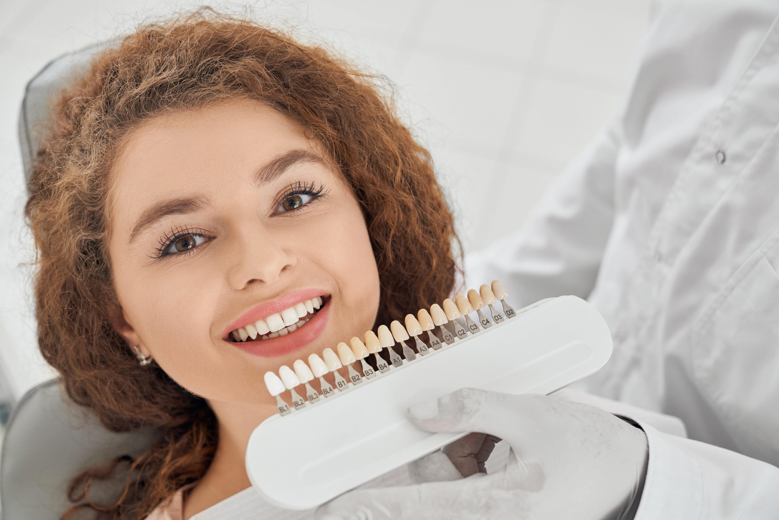woman smiling while dentist keeping measure teeth guide for understanding Same Day Crowns Vs. Traditional Crowns
